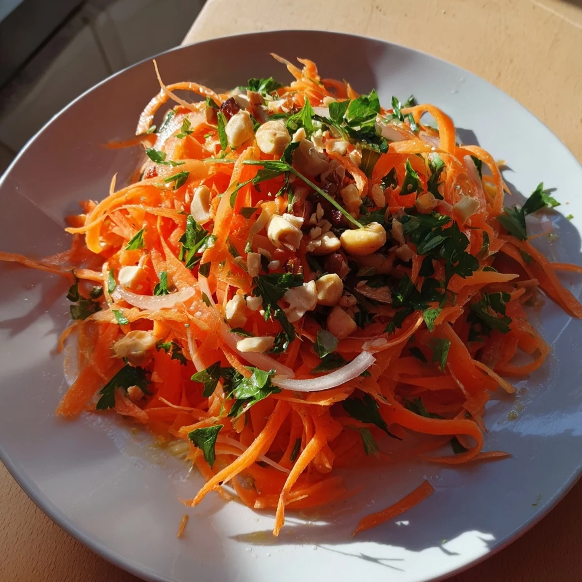 A vibrant bowl of Raw Carrot Salad, topped with fresh parsley and crunchy toppings.