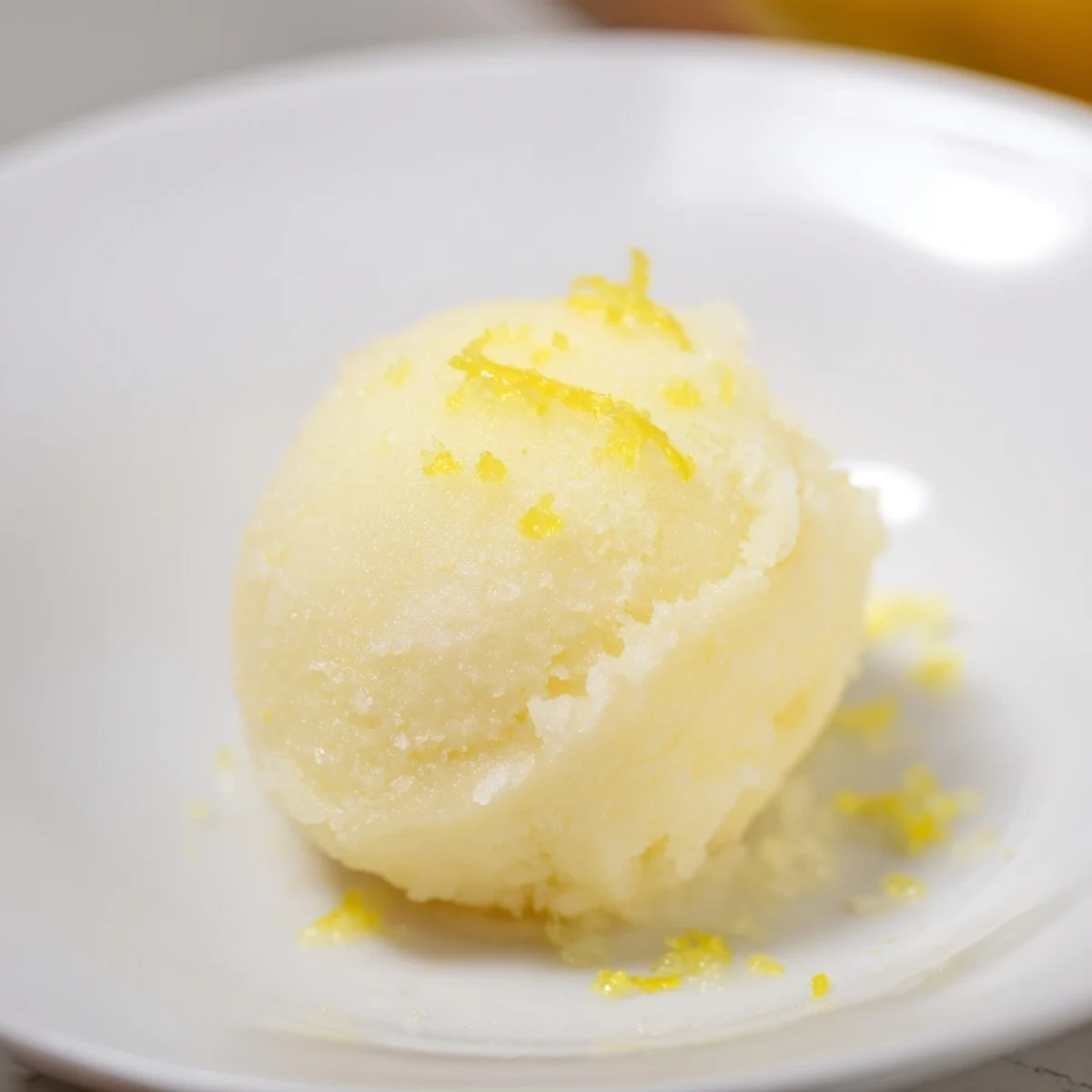 Bright yellow Lemon Sorbet, frozen into creamy perfection, ready to be scooped and enjoyed.