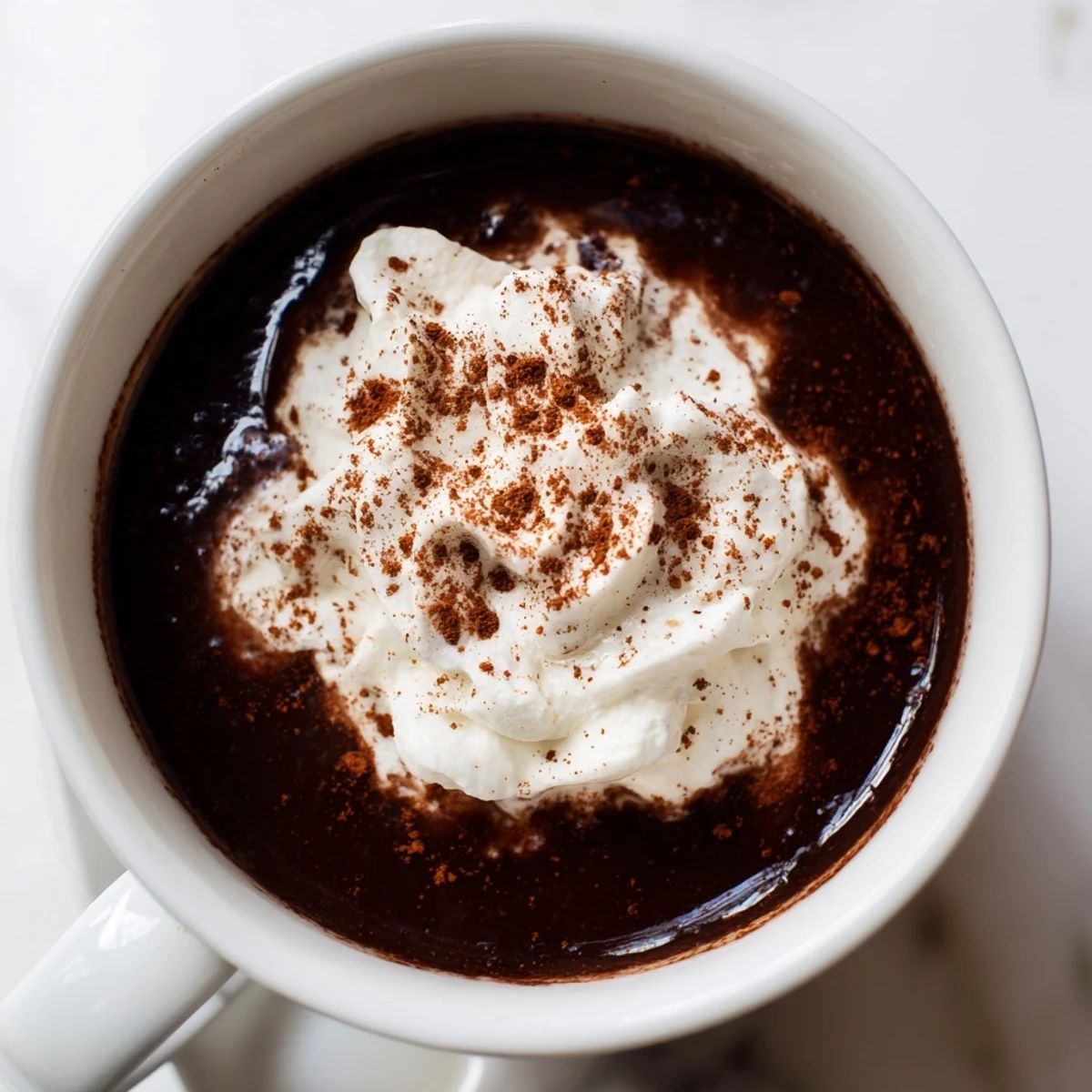 Steaming, spiced hot chocolate topped with fluffy whipped cream, a comforting winter treat.