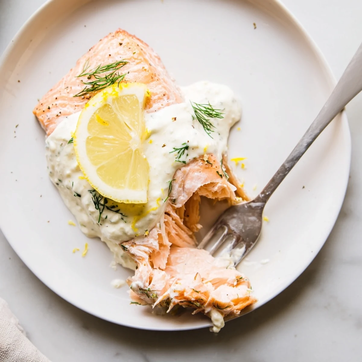 Flaky, oven-baked salmon fillets with bright lemon dill sauce, ready to serve on a plate.