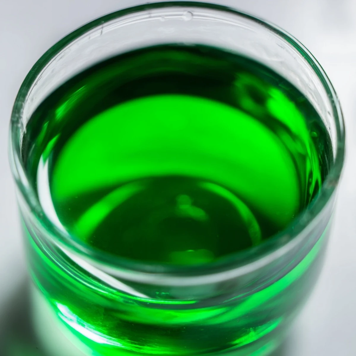 Bright green fresh peppermint leaves submerged in vodka, creating peppermint extract for desserts.
