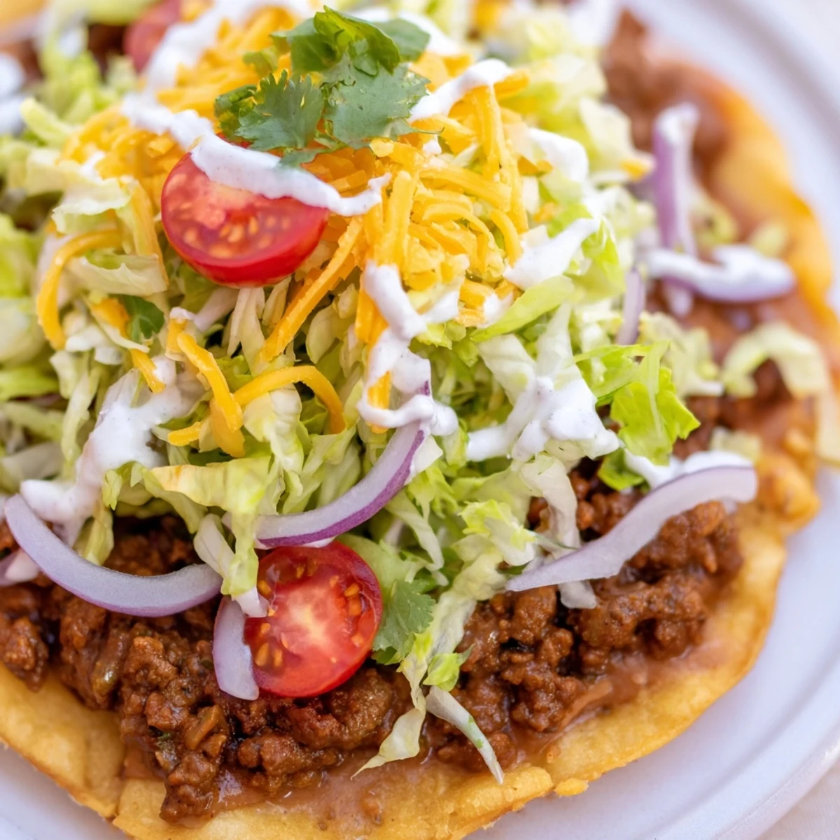 Golden, crispy corn tostada shells piled high with seasoned ground beef and creamy refried beans. Topped with crisp shredded lettuce, juicy tomatoes, and melted cheese for a satisfying crunch.