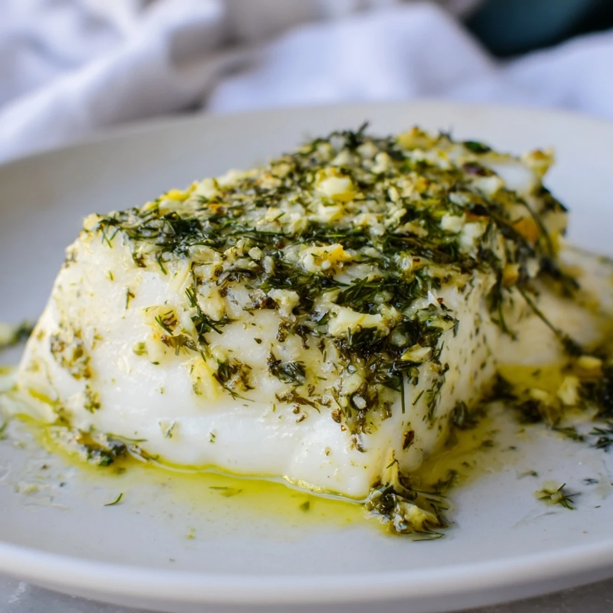 Close-up of tender Baked Halibut with Lemon Herb Butter, showcasing melted butter and herbs on a fresh fillet.