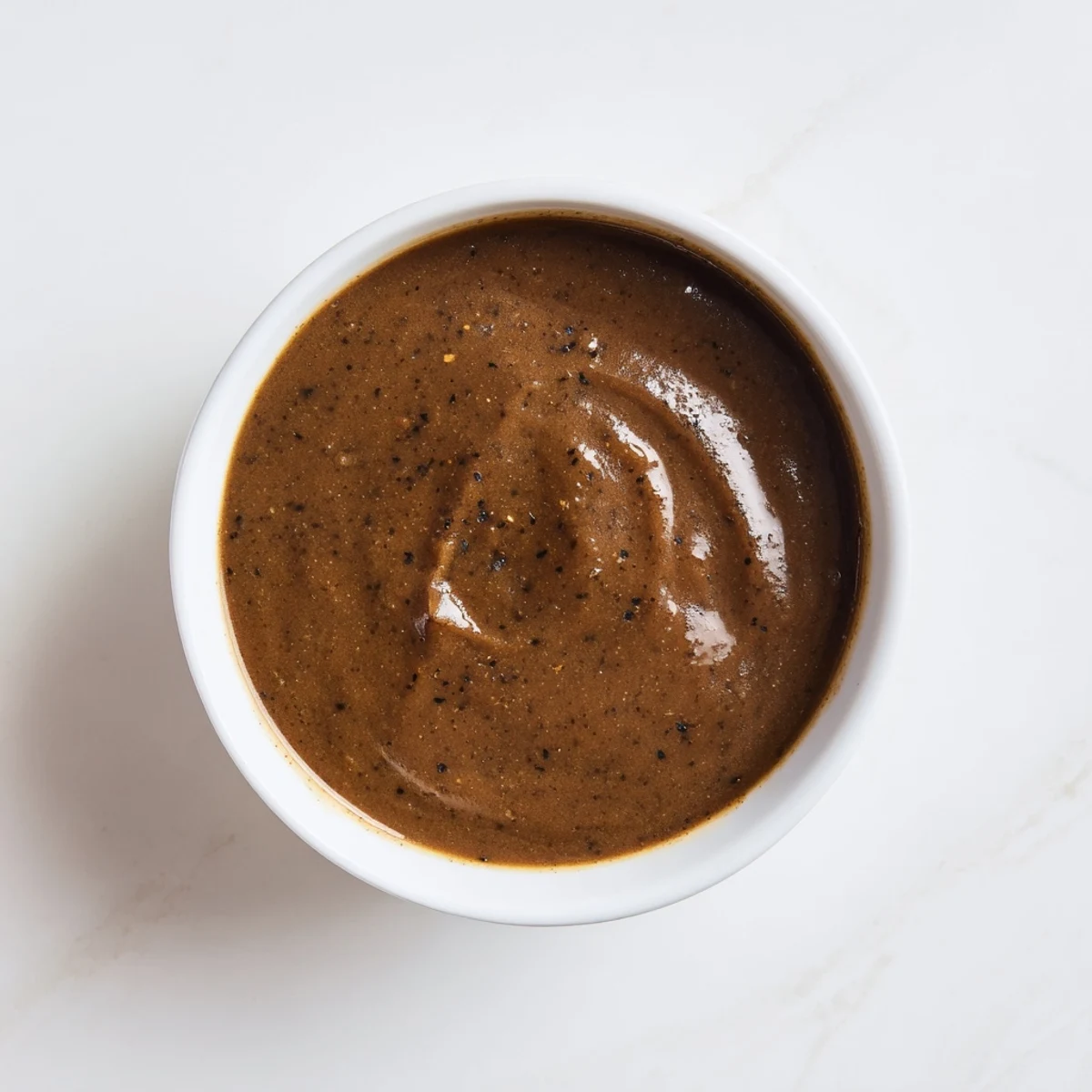 Rich, glossy Beef Gravy with Meat Juice poured over sliced roast beef on a plate.