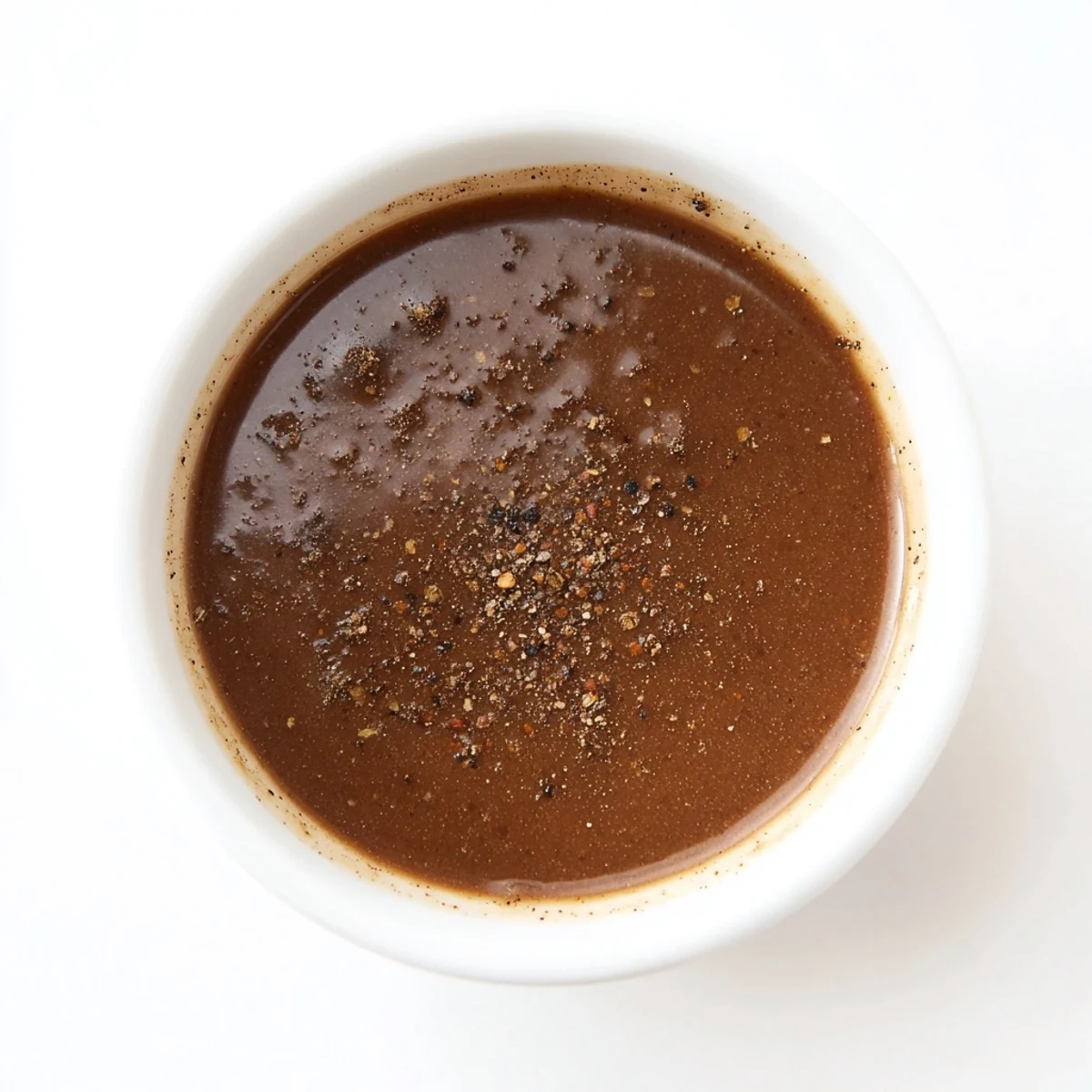 Homemade Beef Gravy with Meat Juice in a white gravy boat over Yorkshire pudding.