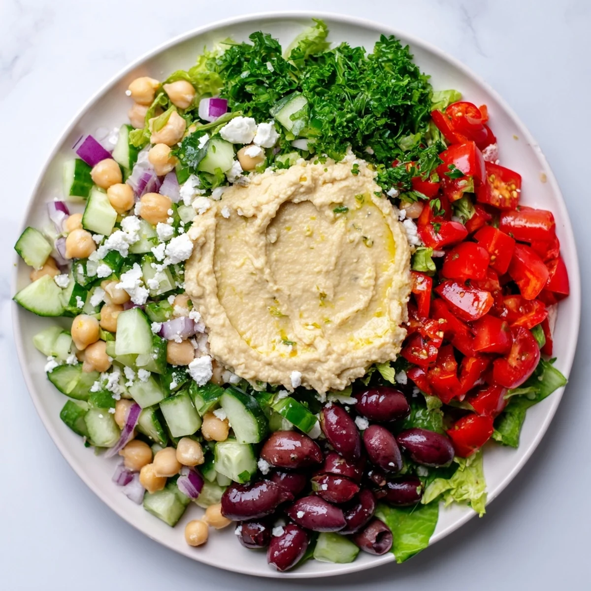 A vibrant Mediterranean Salad with Hummus topped generously with creamy dip, perfect for lunch.