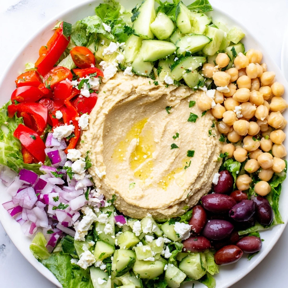 A colorful bowl of Mediterranean Salad with Hummus featuring Kalamata olives, chickpeas, and lemony dressing.