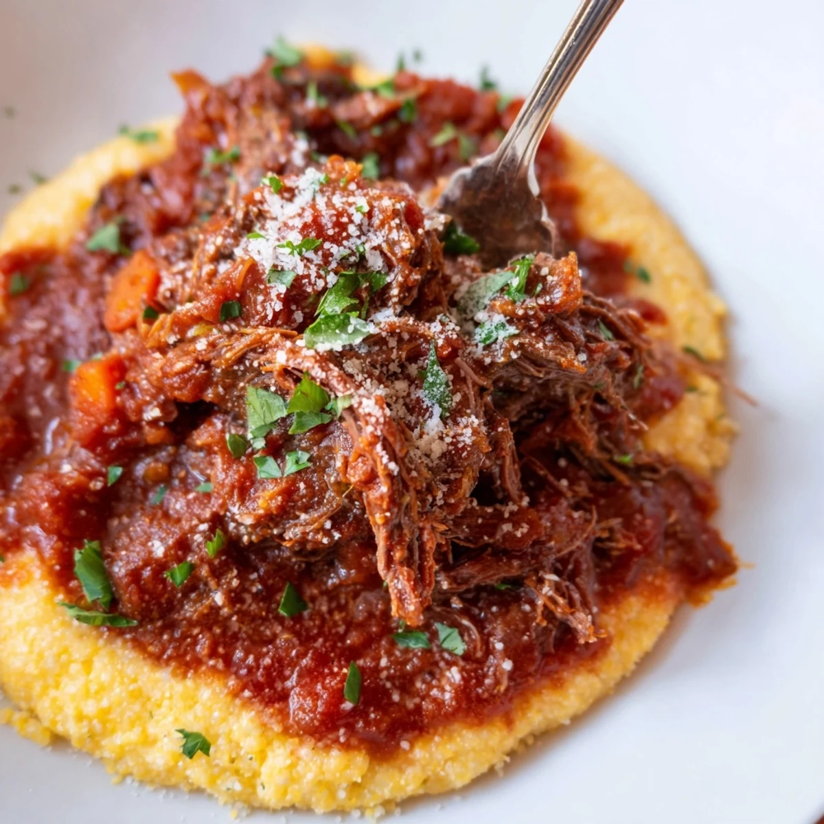 Steaming Slow Cooker Beef Ragu over Polenta in a ceramic bowl, garnished with fresh parsley.