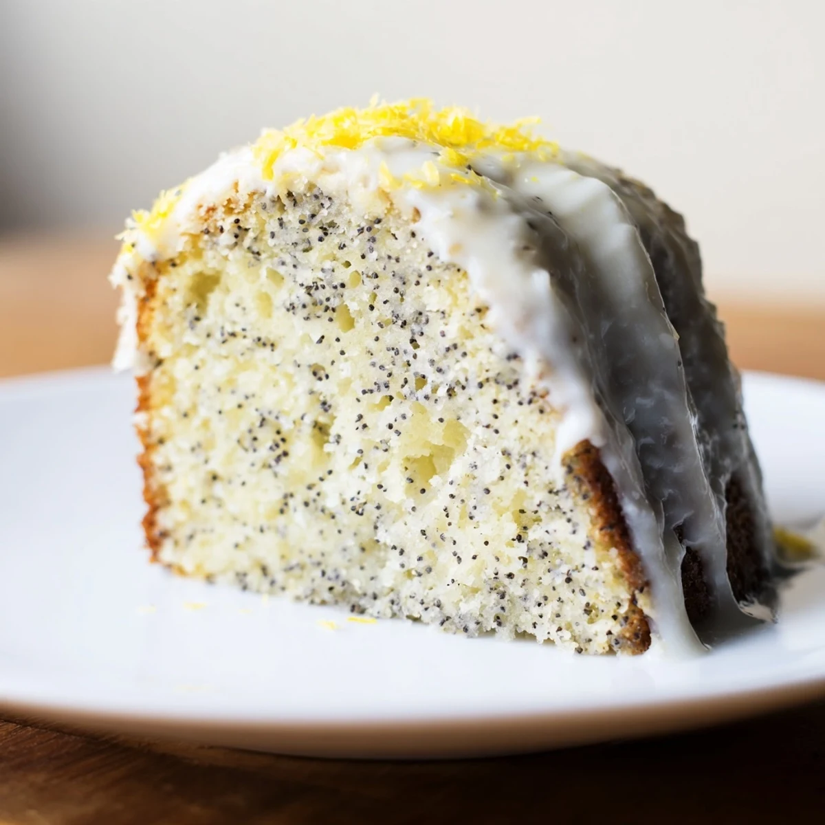 A freshly baked Lemon Poppy Seed Bundt Cake with Lemon Cream Glaze sits on a cooling rack, showing a golden-brown exterior.
