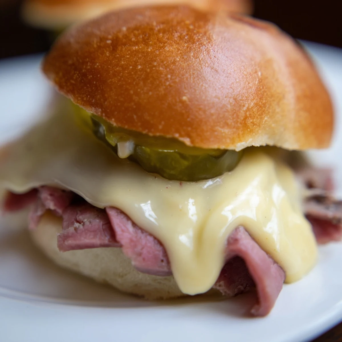 Warm Corned Beef Sliders with melted Swiss cheese and tangy mustard sauce, served fresh from the oven on soft buns.