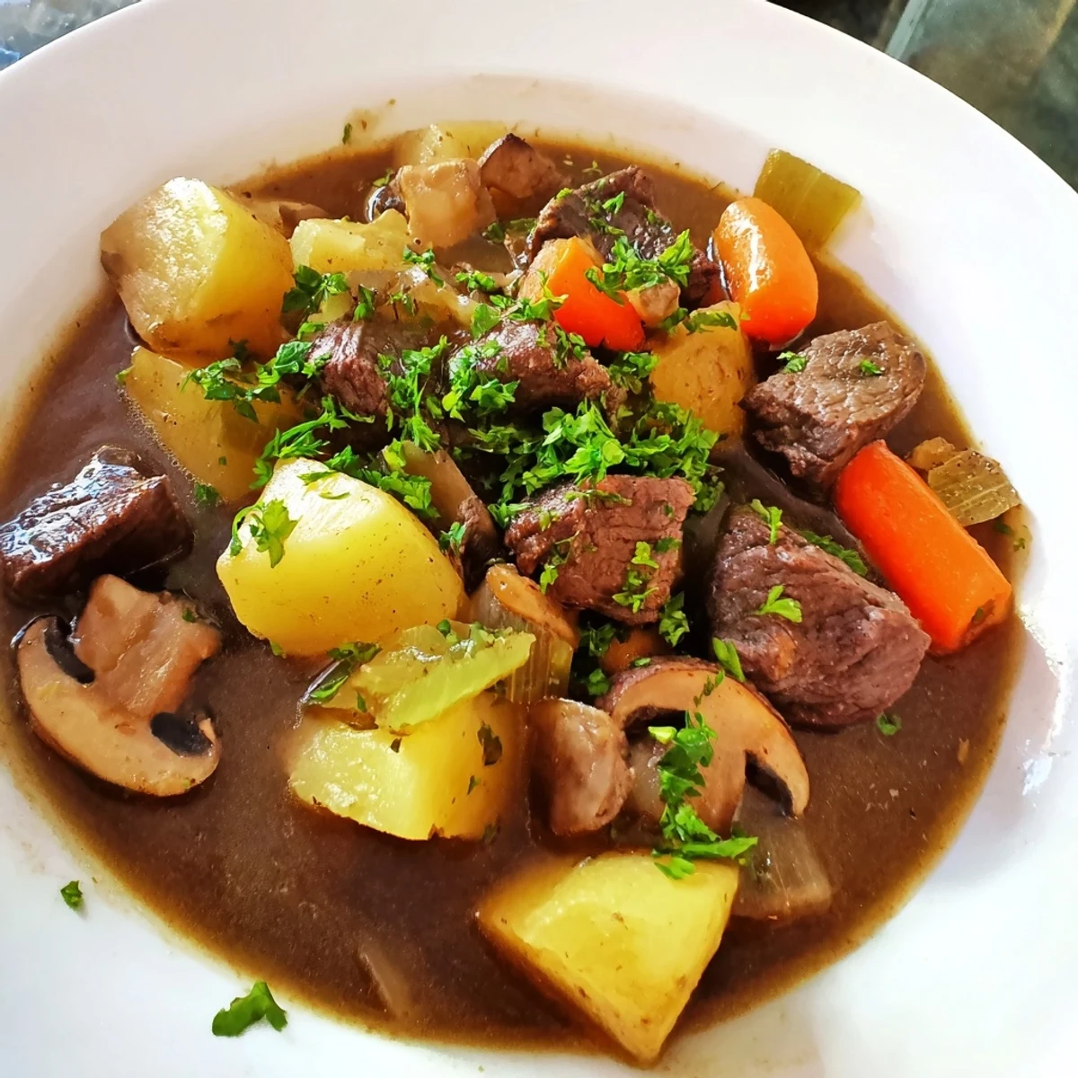 Savory St. Patrick's Day Alcohol-Free Guinness-Style Stew is ladled over creamy mashed potatoes, with crusty bread on the side for dipping.