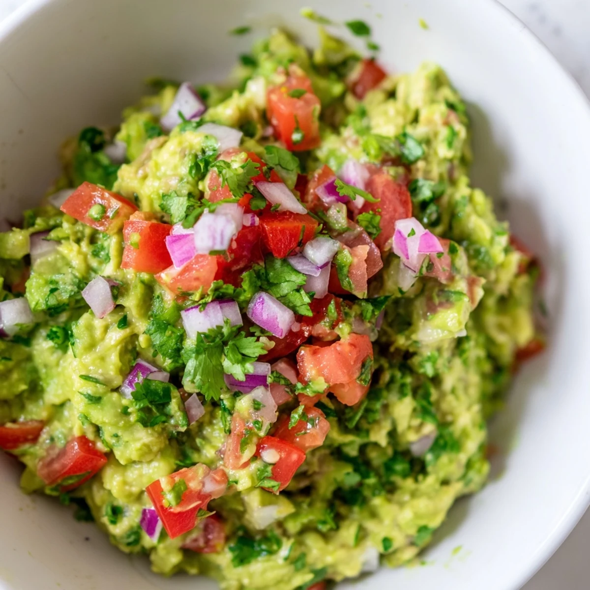 A close-up of Super Bowl Guacamole with Pico de Gallo, featuring creamy avocado chunks and diced tomatoes, onions, and jalapeños.