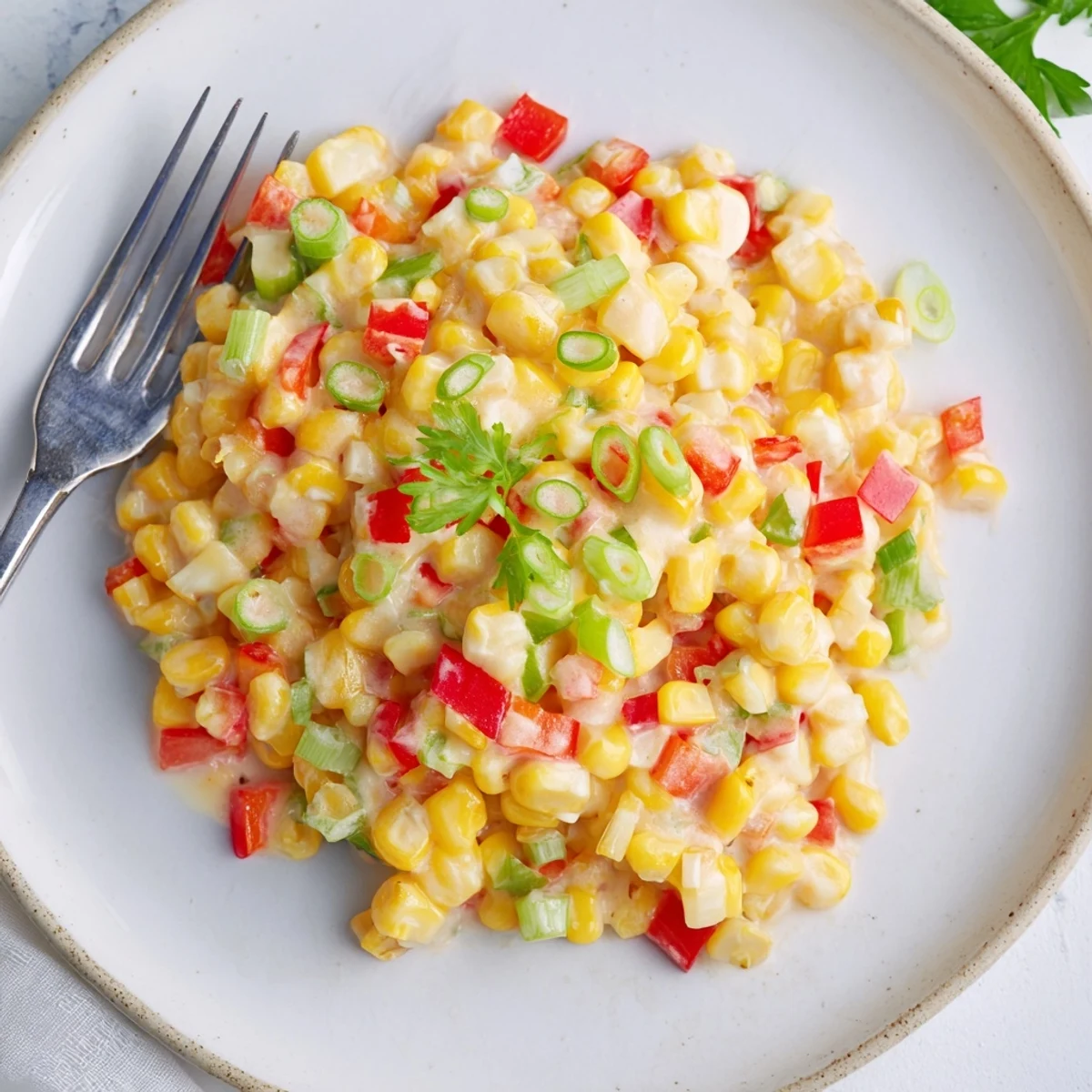 A skillet of Creole Corn Maque Choux with Peppers, featuring creamy corn and colorful diced bell peppers, garnished with fresh parsley.
