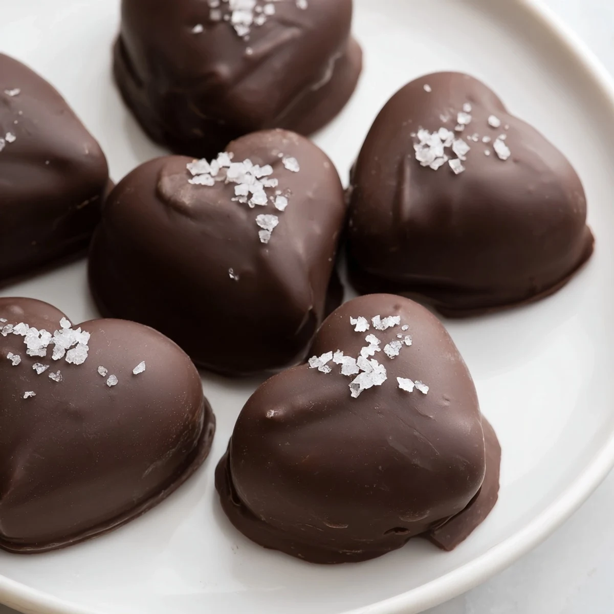 A batch of chocolate peanut butter hearts with sea salt, arranged on parchment paper for an easy-to-serve dessert.