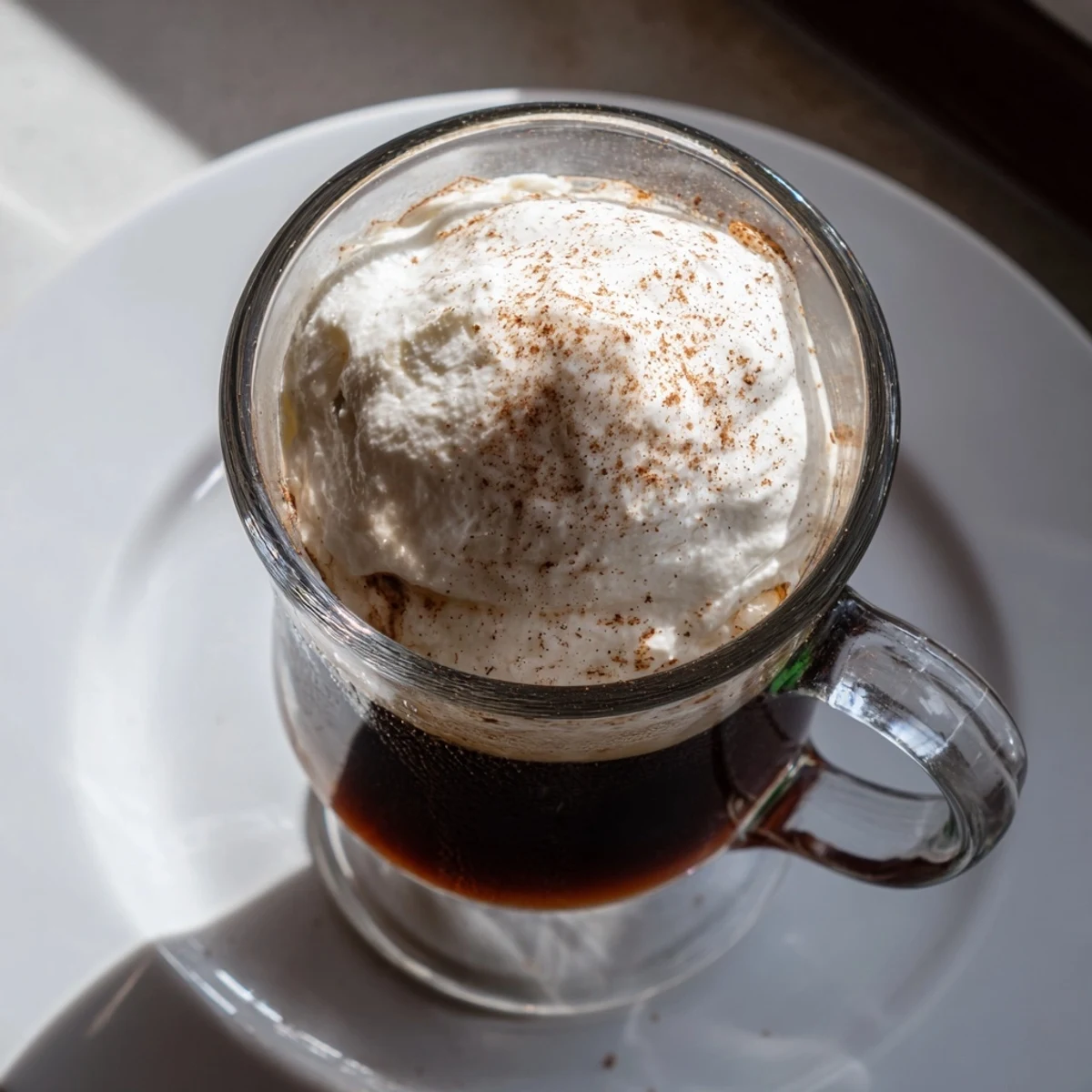 Two servings of the non-alcoholic Irish Coffee Mocktail topped with fluffy whipped cream, ready to enjoy on a cold day.