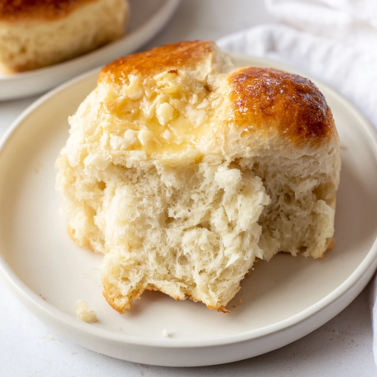Twelve warm, tender Best Vegan Dinner rolls on a wooden board, with a pat of vegan butter melting on top.