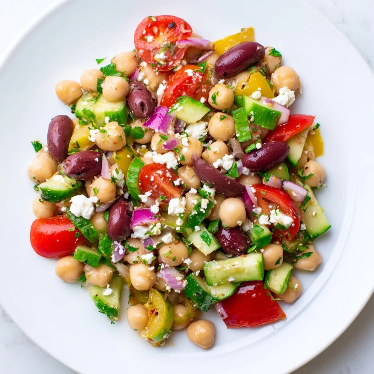 Overhead view of Mediterranean Dense Bean Salad with vibrant vegetables and herbs on a rustic wooden table, ready to serve.