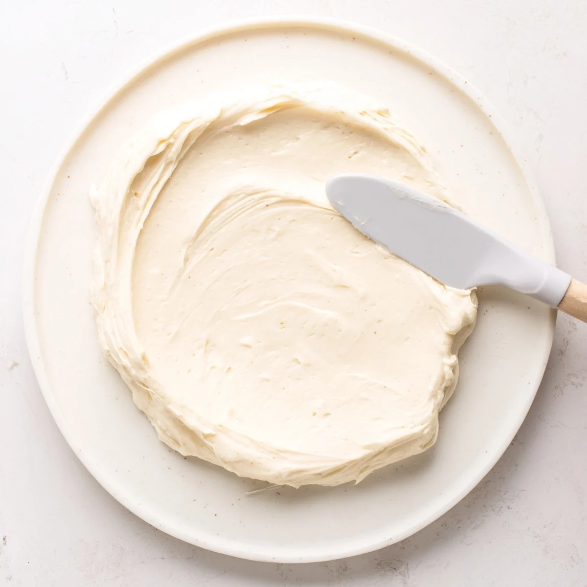 A close-up of sugar cookies with Easy Sugar Cookie Frosting swirled on top, showing a smooth and glossy finish.  