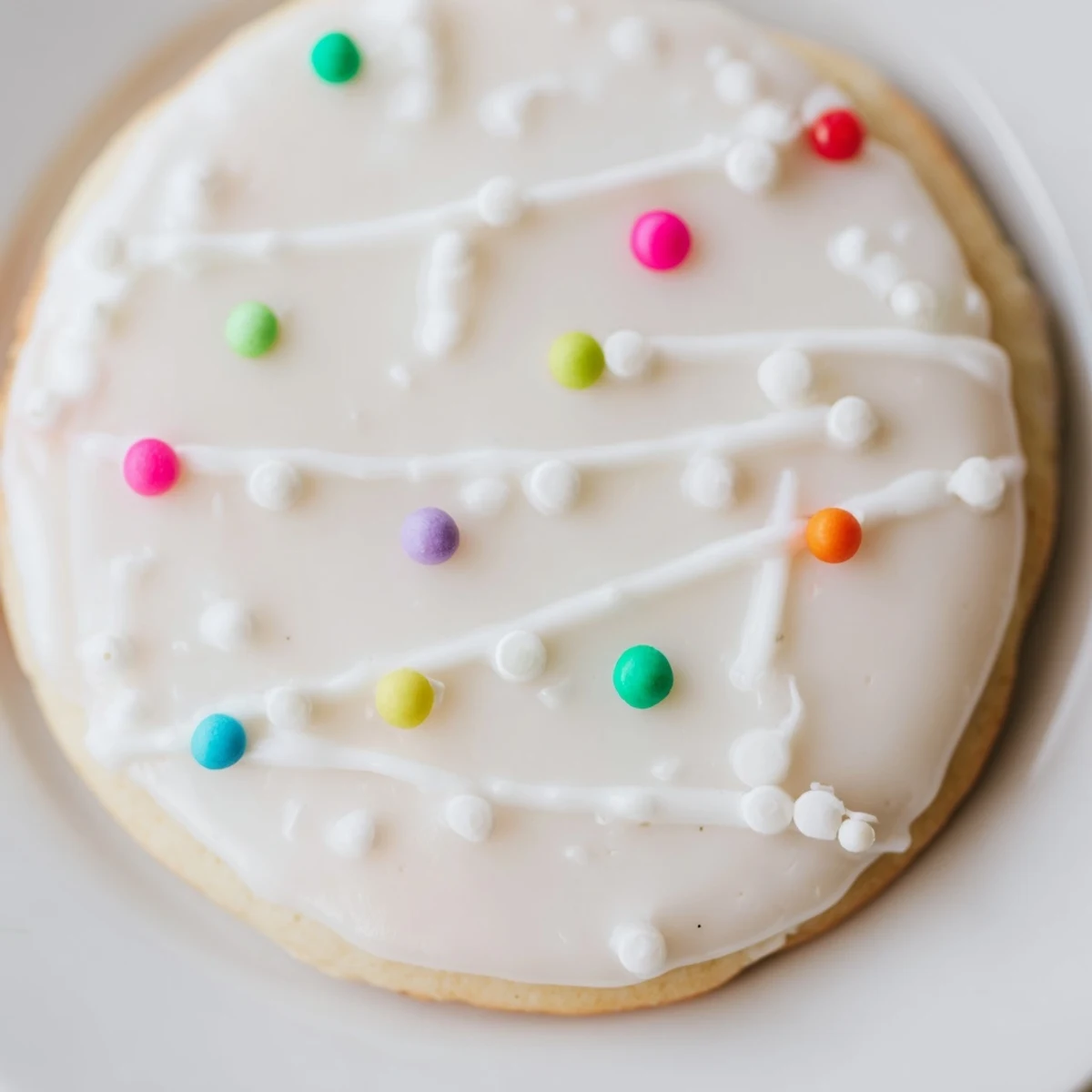 Sugar Cookie Icing being piped onto decorated cookies, creating vibrant patterns and a perfect glossy finish for parties.