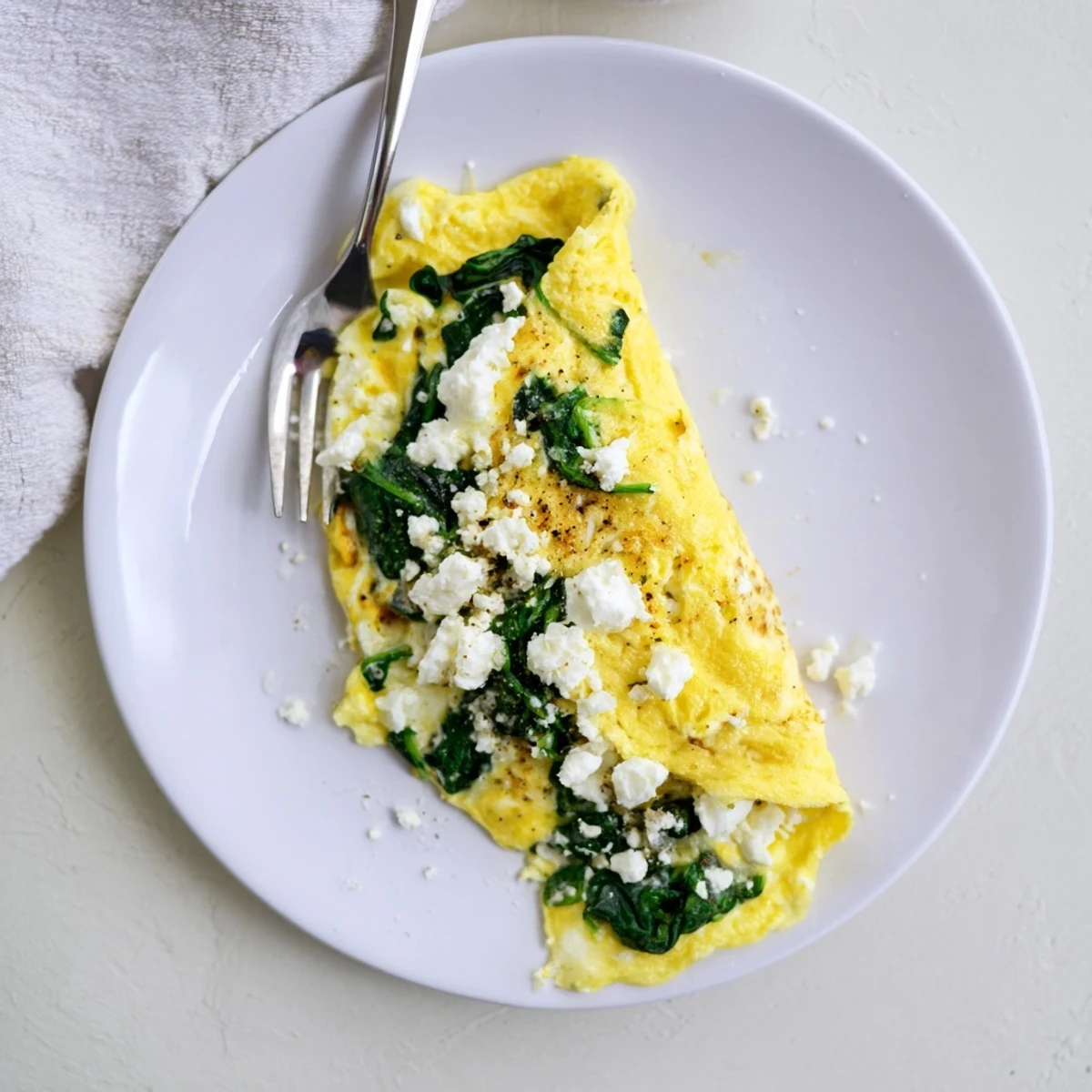 Golden-brown 15-Minute Spinach and Feta Omelet folded neatly, served beside a slice of whole-grain toast.