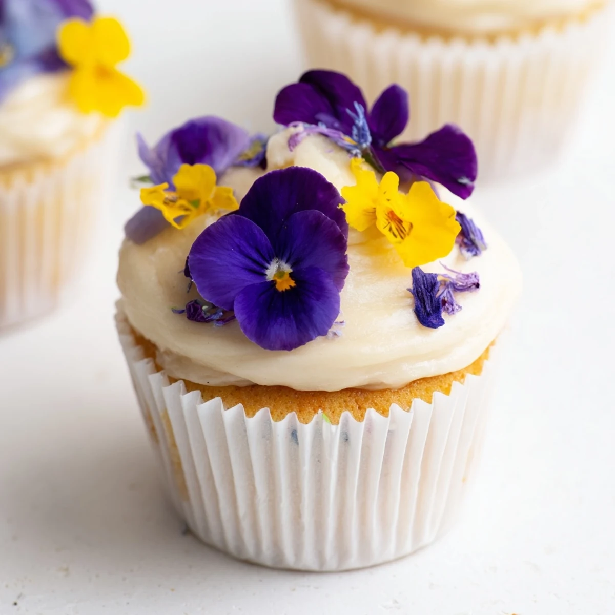 Lightly frosted Wild Flower Cupcakes topped with edible blossoms and perfect for a spring afternoon tea.