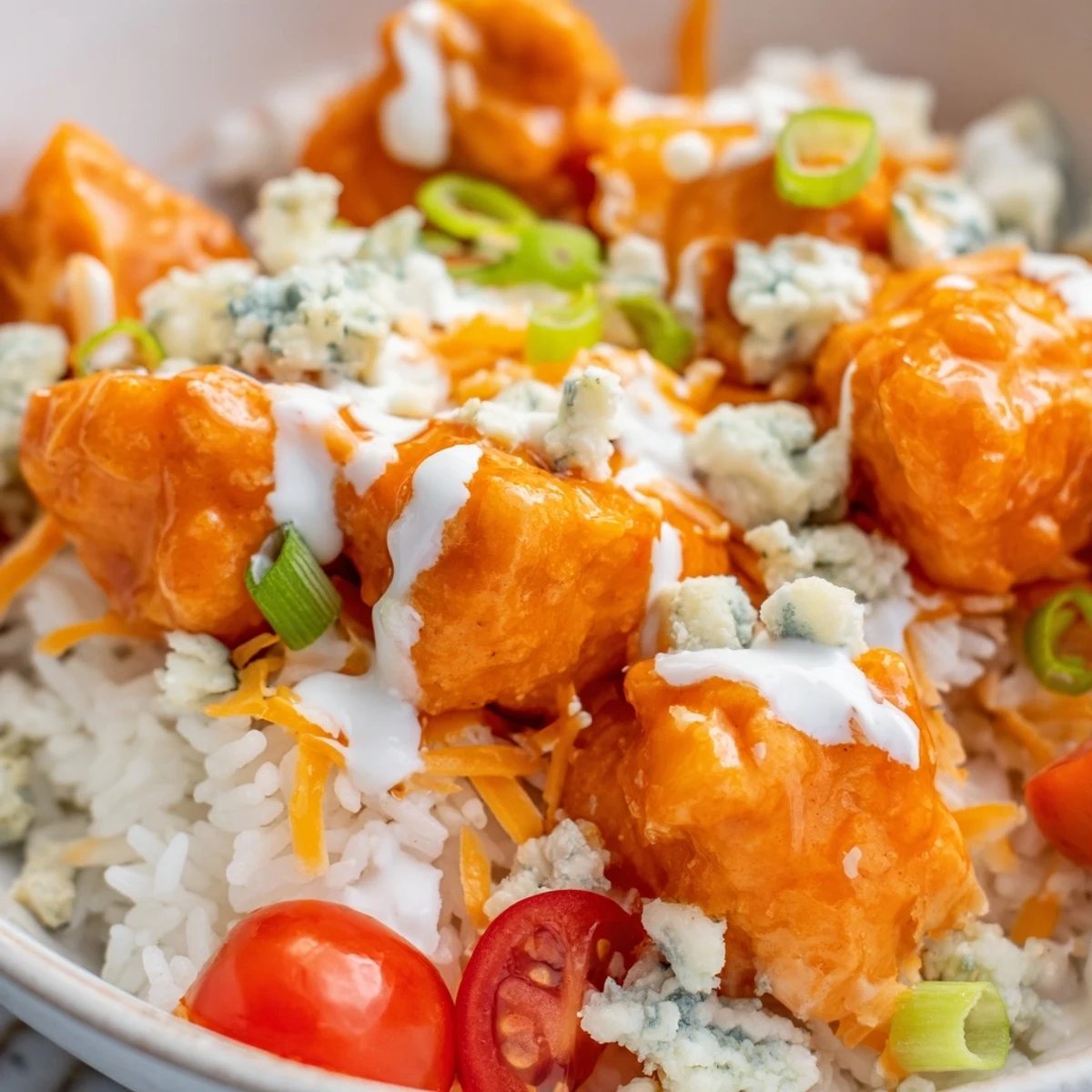 Spicy buffalo chicken, cool ranch, and crunchy toppings over rice create a vibrant, hearty meal bowl.
