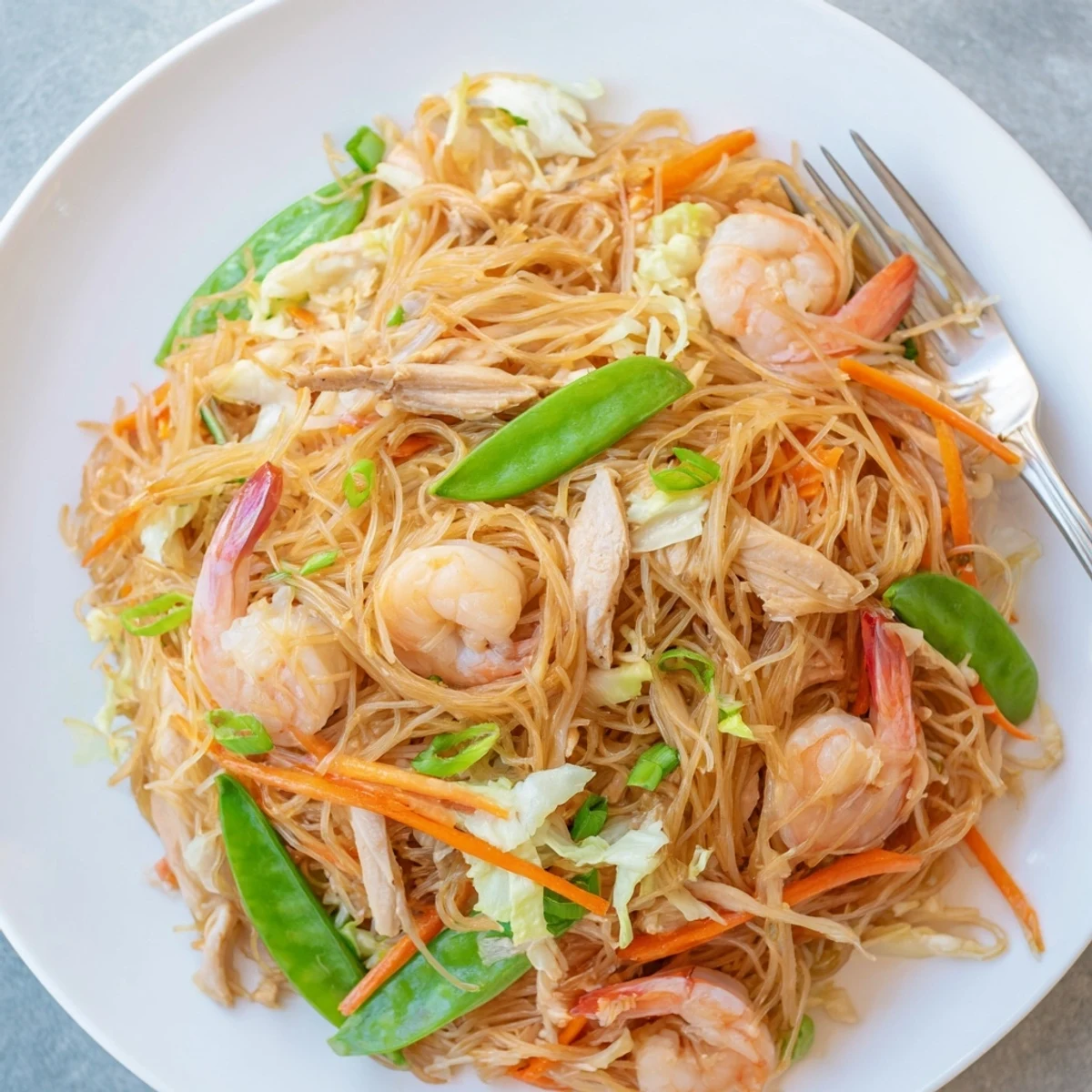 Hearty Filipino traditional Pancit Bihon stir-fry showcasing juicy shrimp and vegetables in savory soy sauce