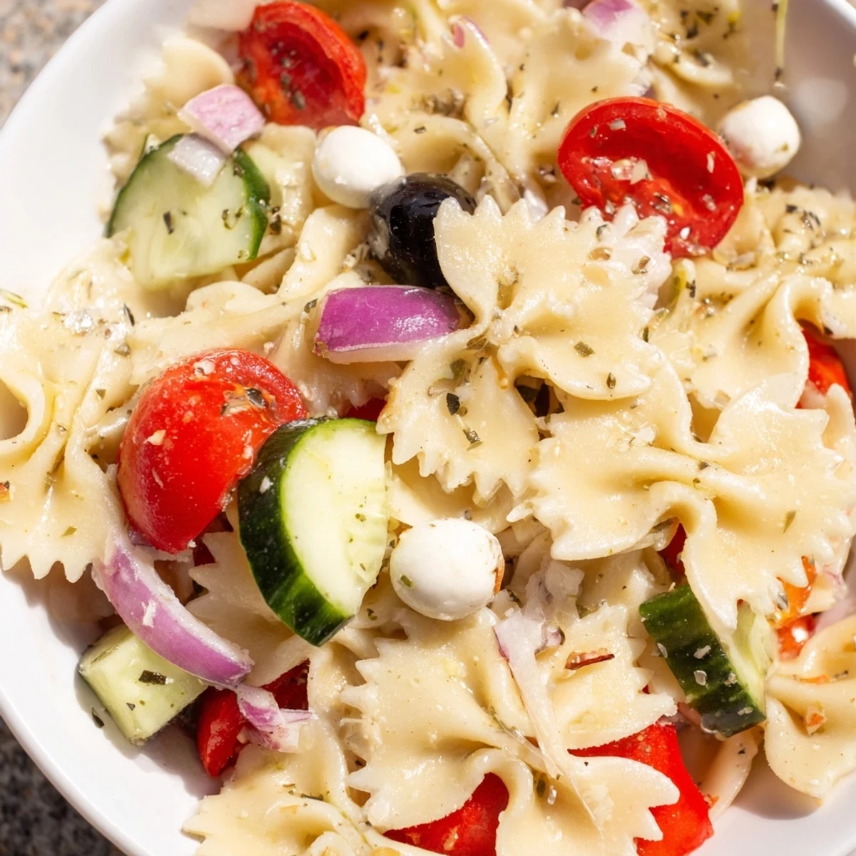 Refreshing bowl of farfalle pasta tossed with crisp vegetables and zesty Italian dressing for summer gatherings