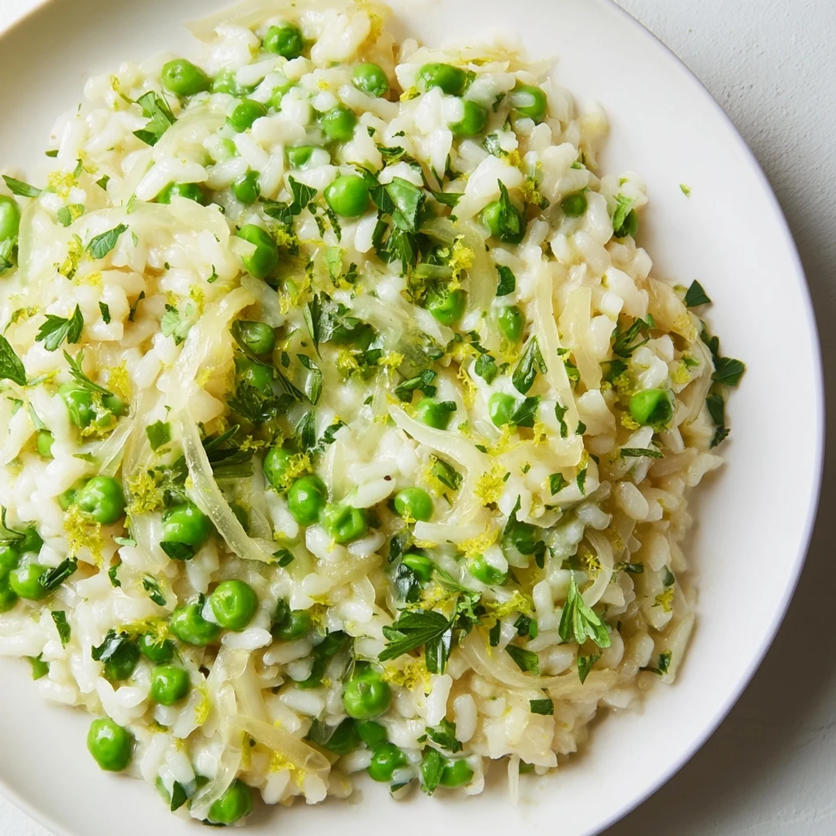 Creamy spring pea risotto topped with grated Parmesan and fresh green parsley herbs