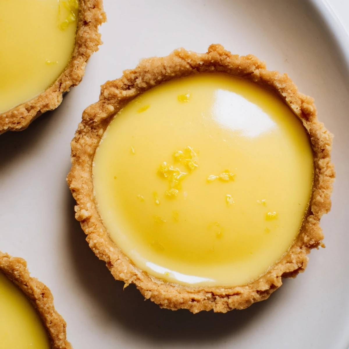 Twelve tangy lemon-filled tart shells arranged on a wooden board with coconut cream filling