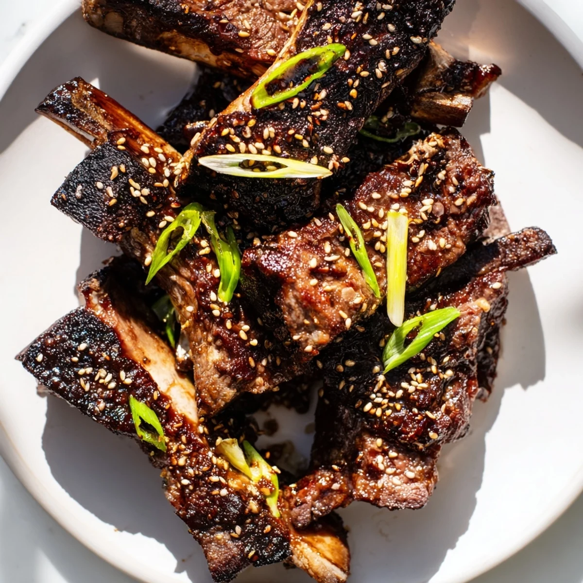 Sizzling Korean Galbi beef short ribs with scallion topping served alongside steamed white rice and kimchi