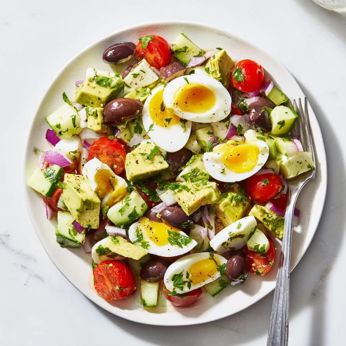 Chopped eggs and ripe avocado tossed with colorful vegetables in a zesty lemon dressing