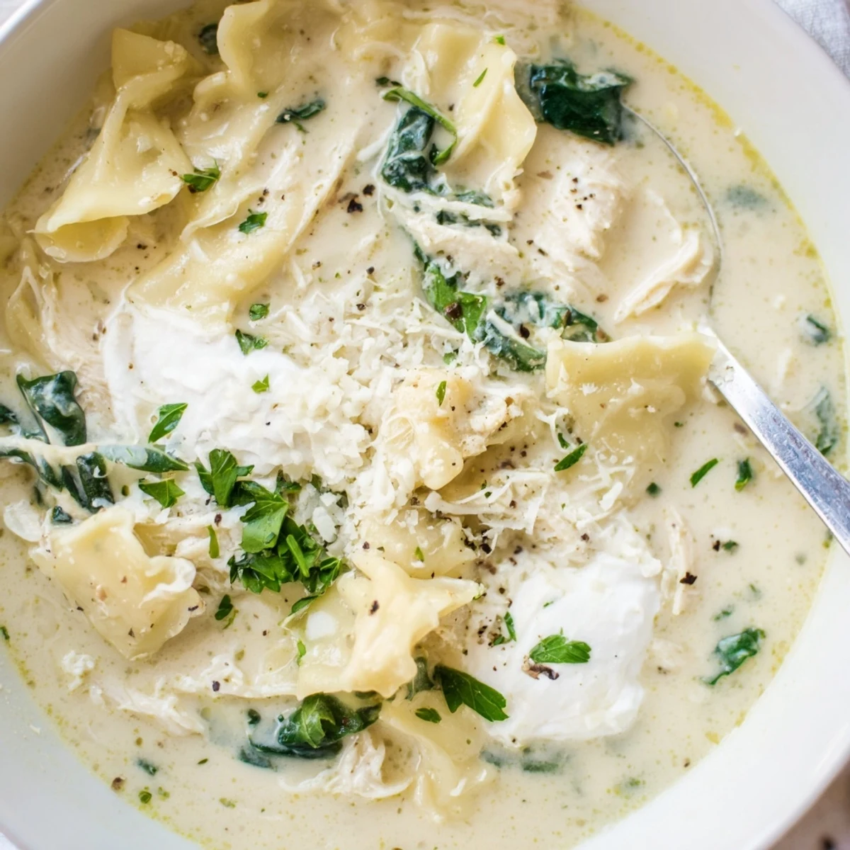 Creamy white lasagna soup with tender chicken, spinach, and broken noodles in Parmesan broth