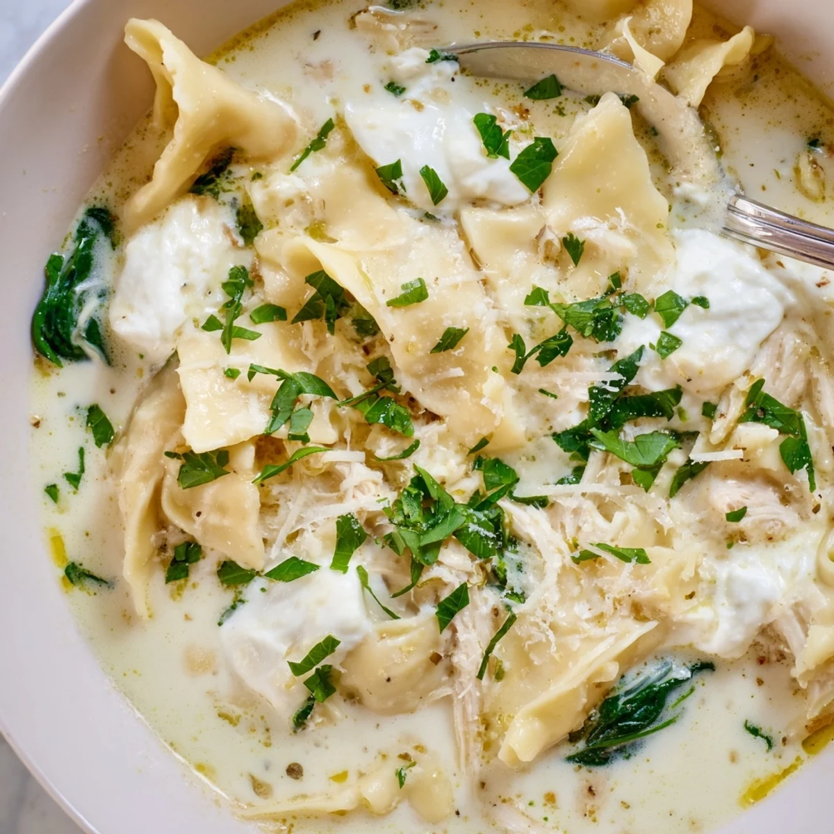 Steaming bowl of white lasagna soup topped with melted mozzarella and fresh parsley