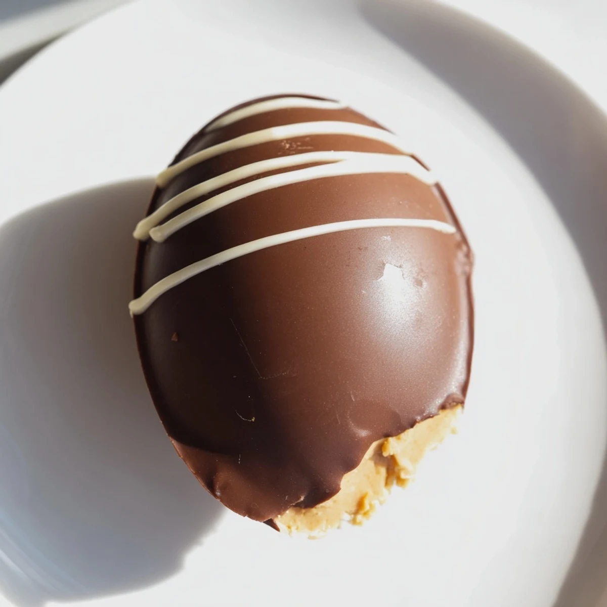 Creamy peanut butter Easter eggs on white plate with chocolate coating and decorative white drizzle