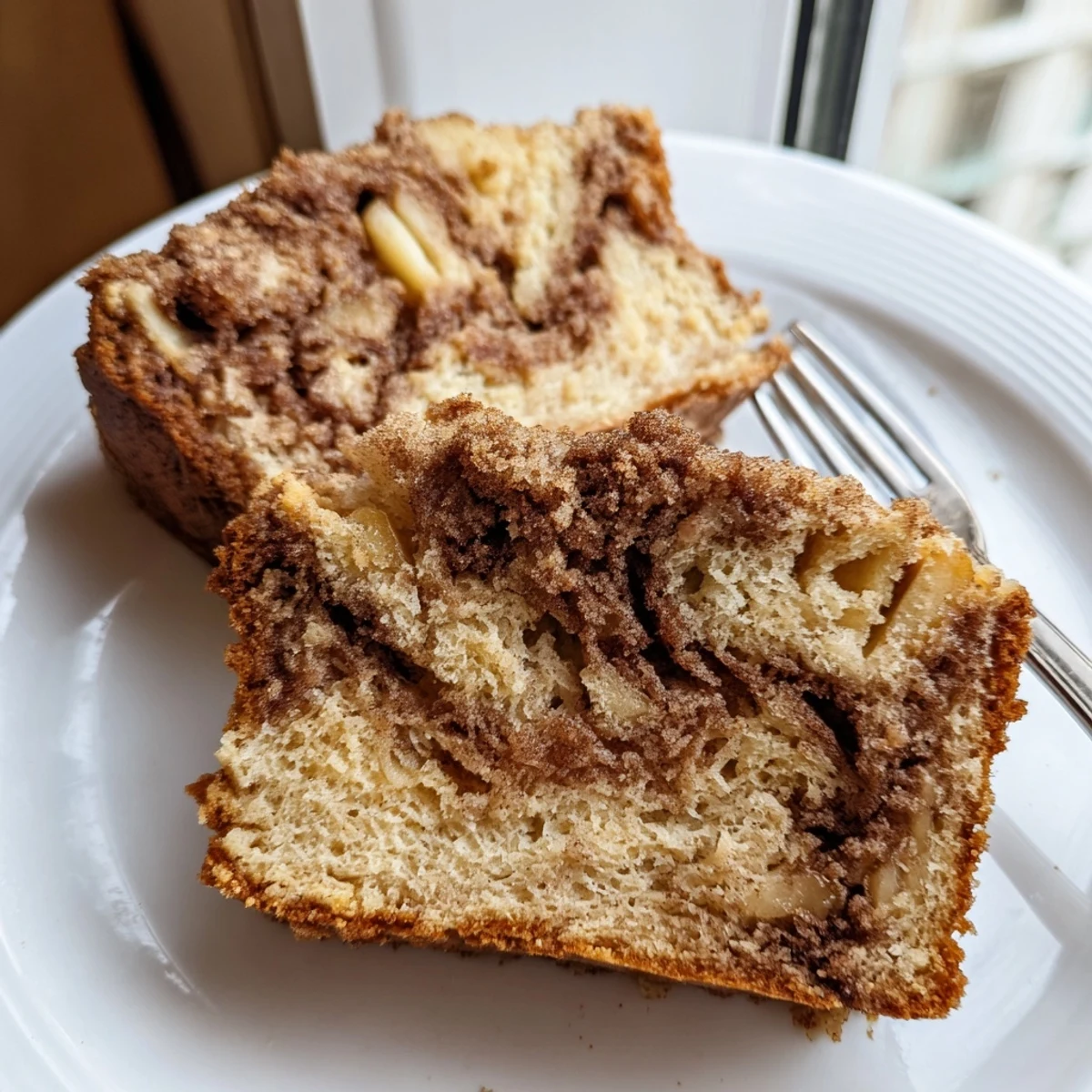 Golden cinnamon apple bread loaf with a marbled sugar swirl topping and peeled diced apples folded throughout the moist tender crumb