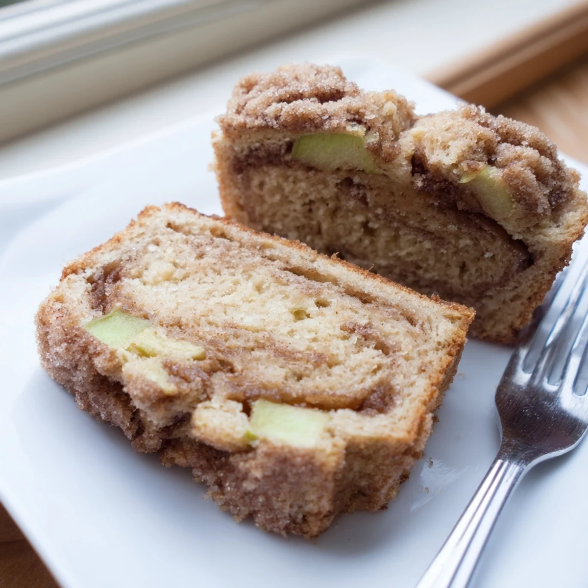 Warm slice of cinnamon apple bread on a wire rack showing the cinnamon sugar ribbons and chunky apple pieces