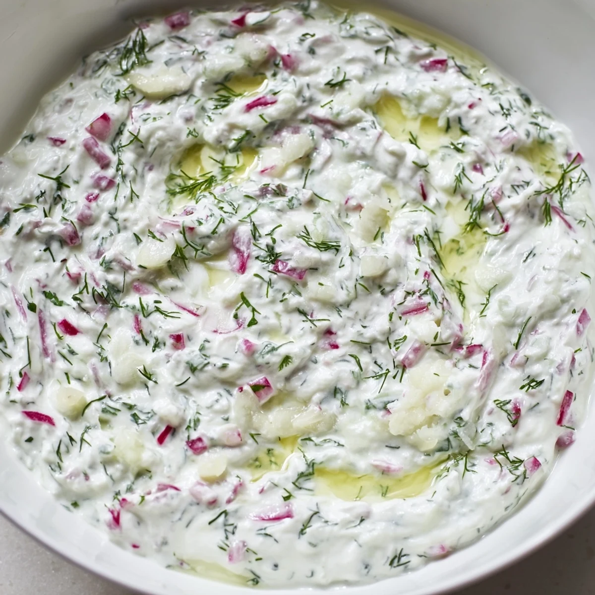 White bowl of healthy radish tzatziki dip served with crisp vegetable crudités