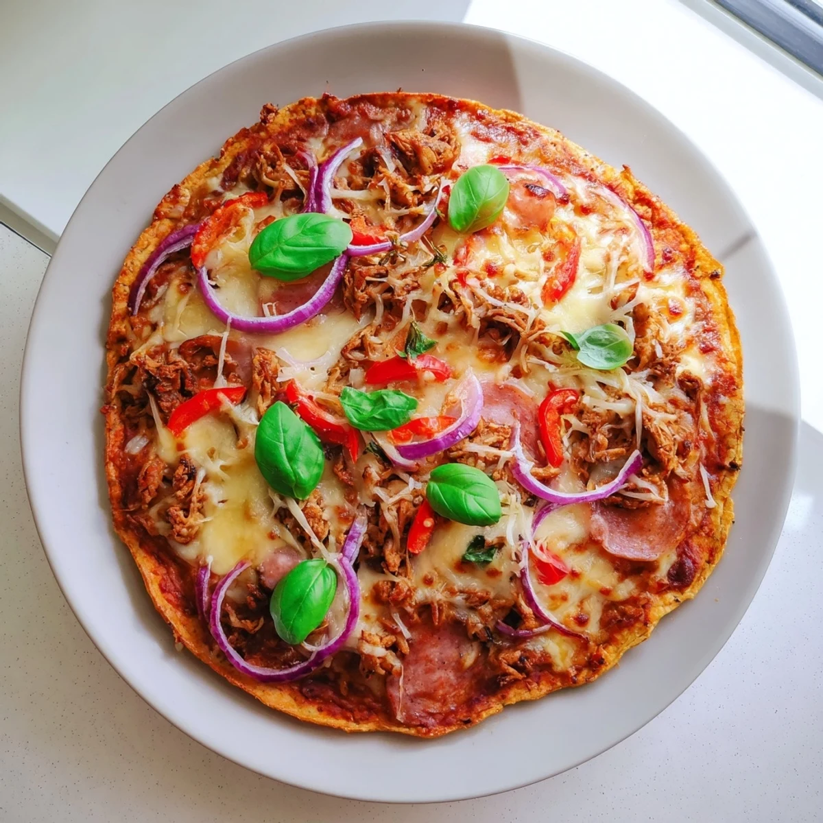 Low-carb chicken crust pizza bubbling with cheese and colorful sliced vegetables on a golden base
