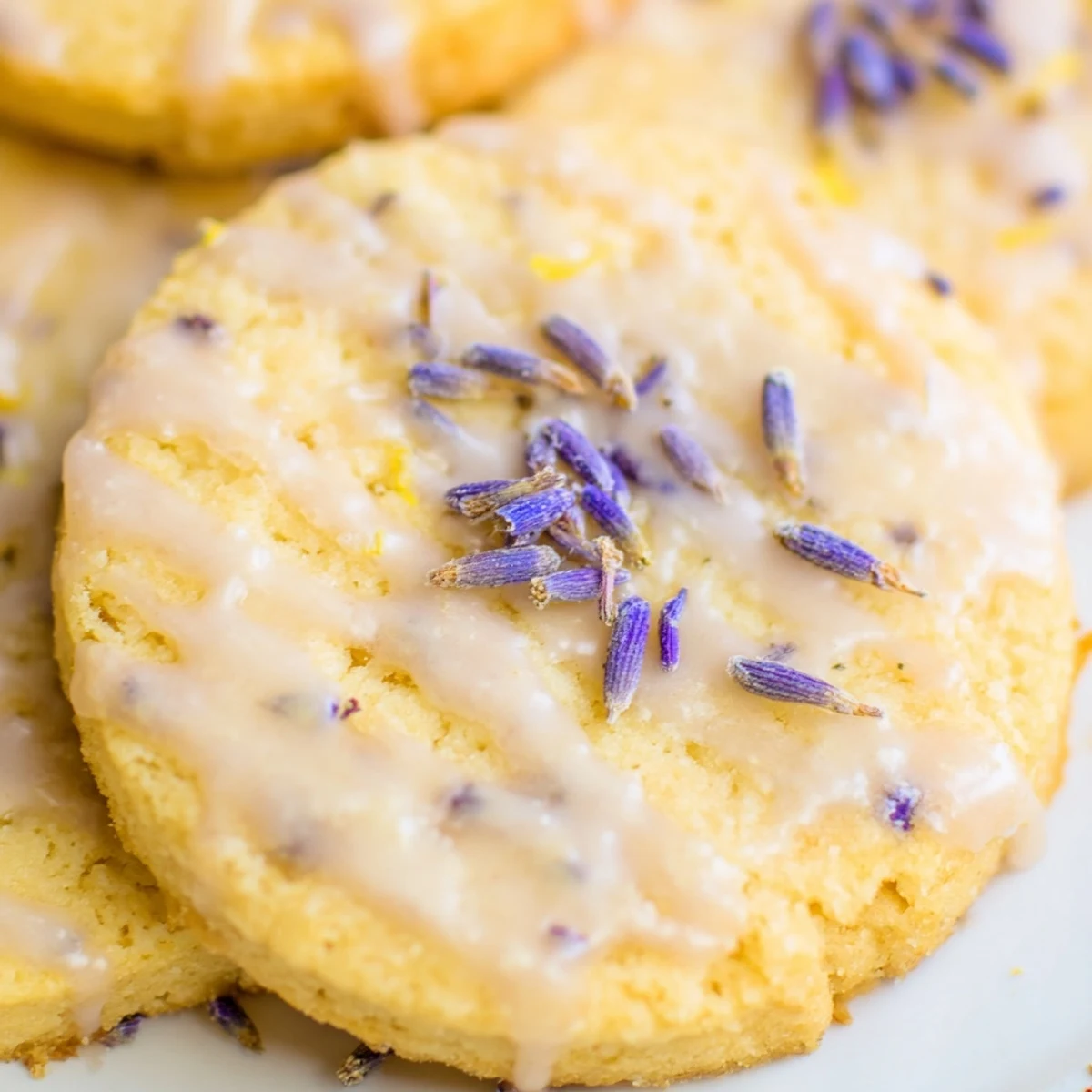 Iced Lemon Lavender Shortbread Cookies drizzled with glossy citrus icing on a rustic white plate