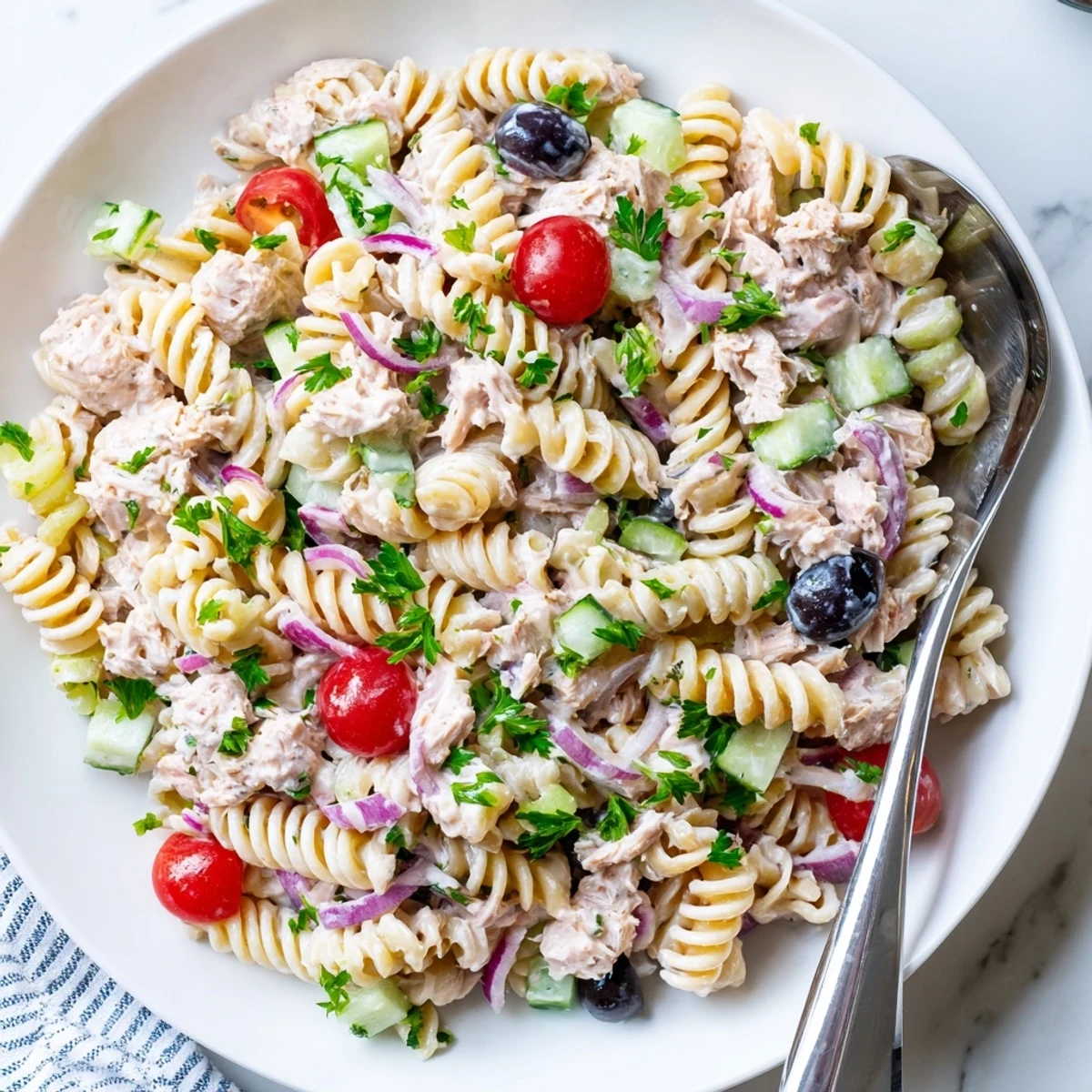 Creamy tuna pasta salad in a white bowl with colorful fresh vegetables and tender spiral noodles