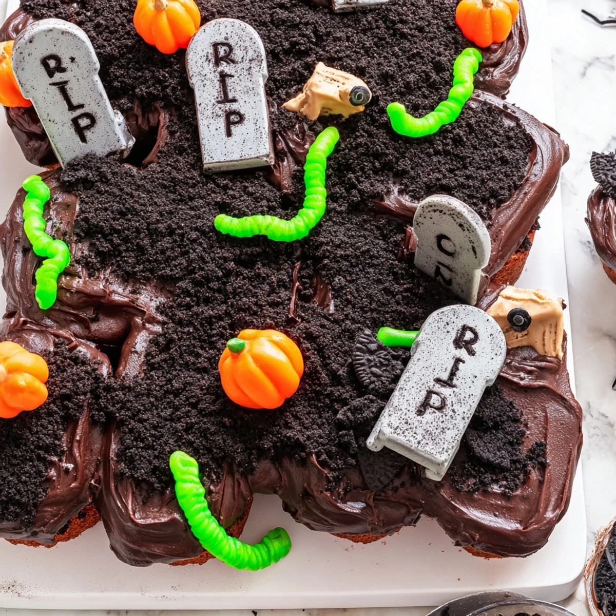 Chocolate frosted pull apart graveyard cupcakes arranged on a tray with creepy candy details