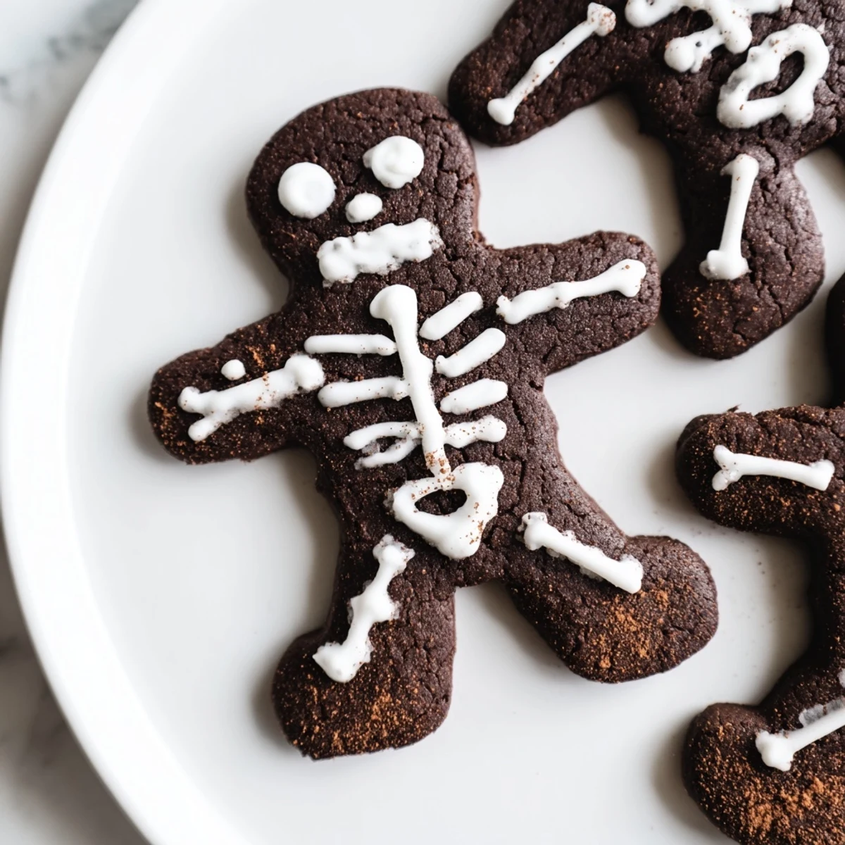 Dark chocolate cinnamon skeleton cookies decorated with white icing on a rustic baking sheet