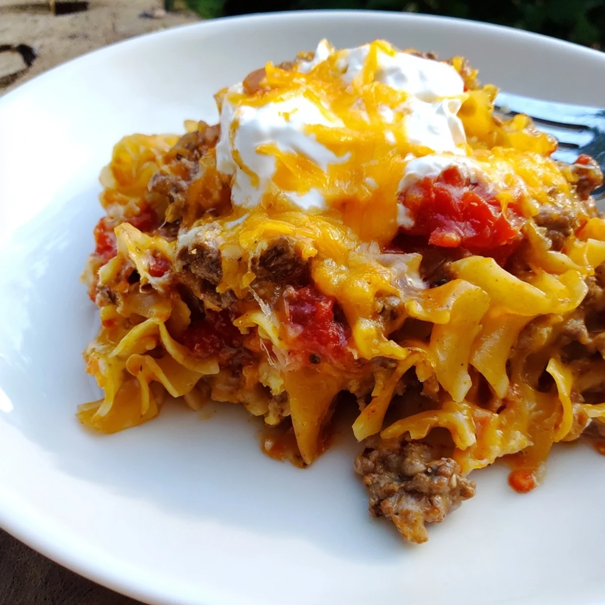 Beef Lombardi Casserole bubbling golden with melted cheddar, steaming next to salad
