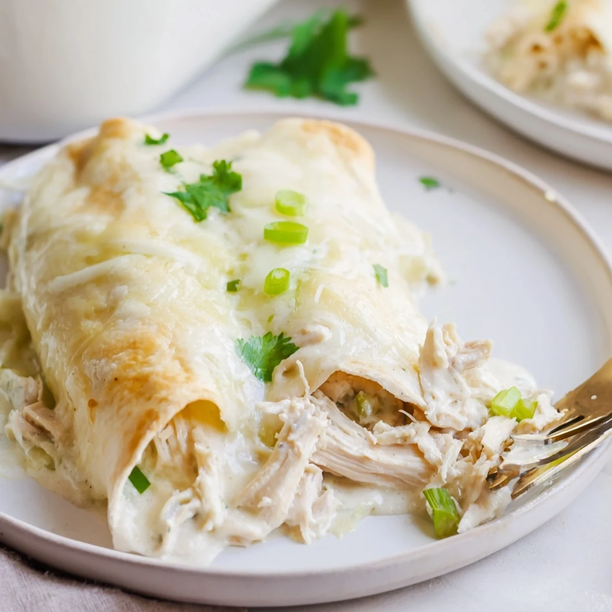 Creamy White Chicken Enchiladas bubbling in casserole dish, golden edges, garnished with cilantro