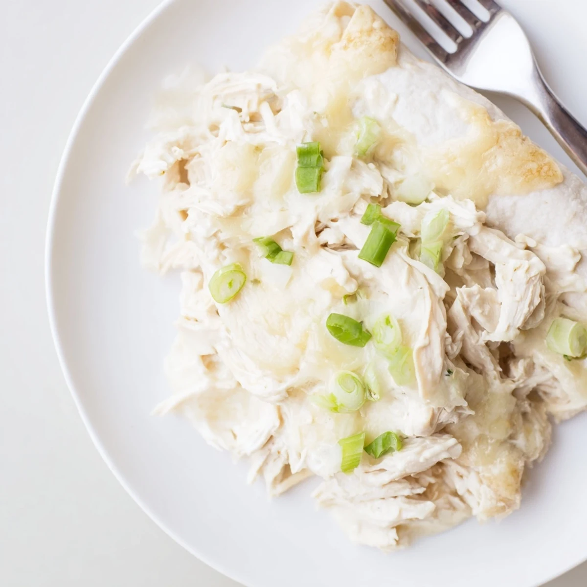 Plated with Spanish rice, Creamy White Chicken Enchiladas topped with chopped cilantro
