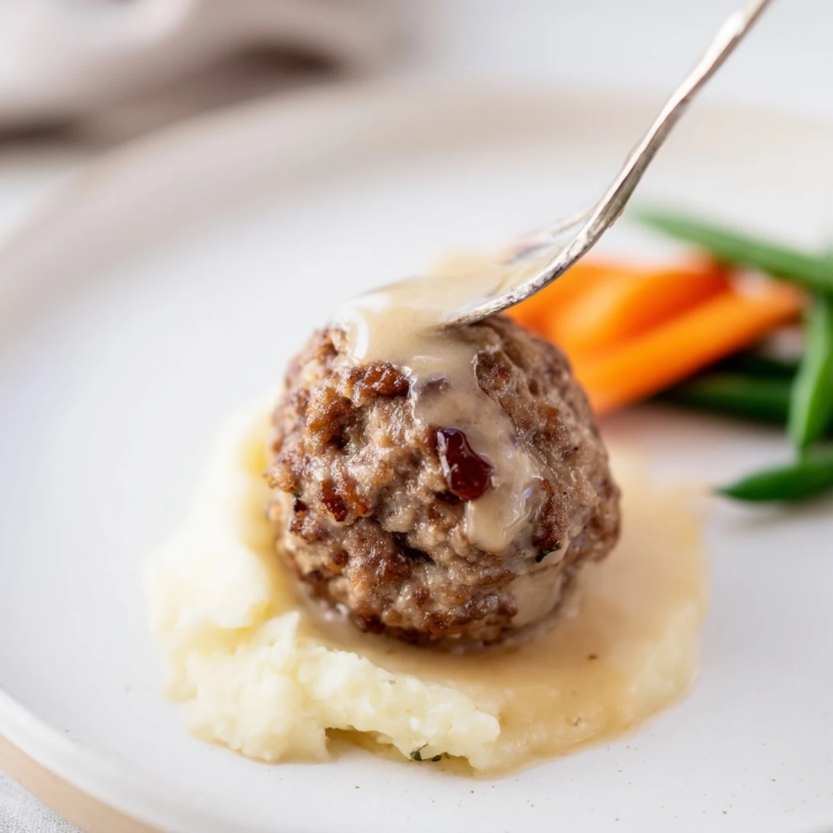 Sizzling skillet of Homemade Ikea Meatballs, browned and topped with creamy gravy