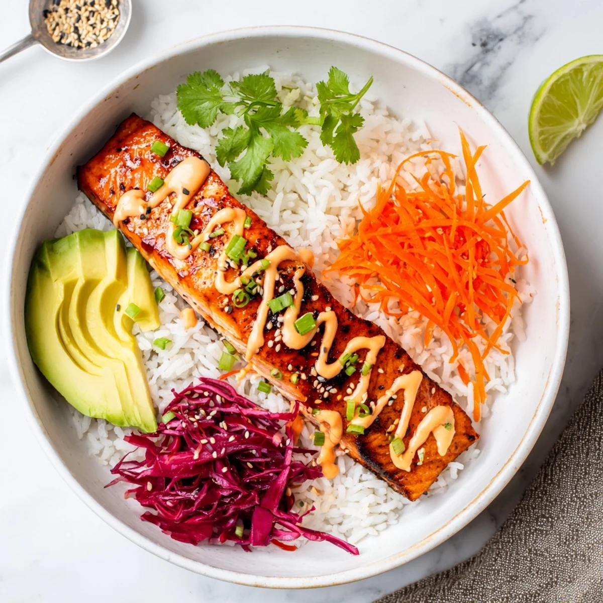 Warm Bang Bang Salmon Bowls topped with sesame seeds, cilantro, lime wedge