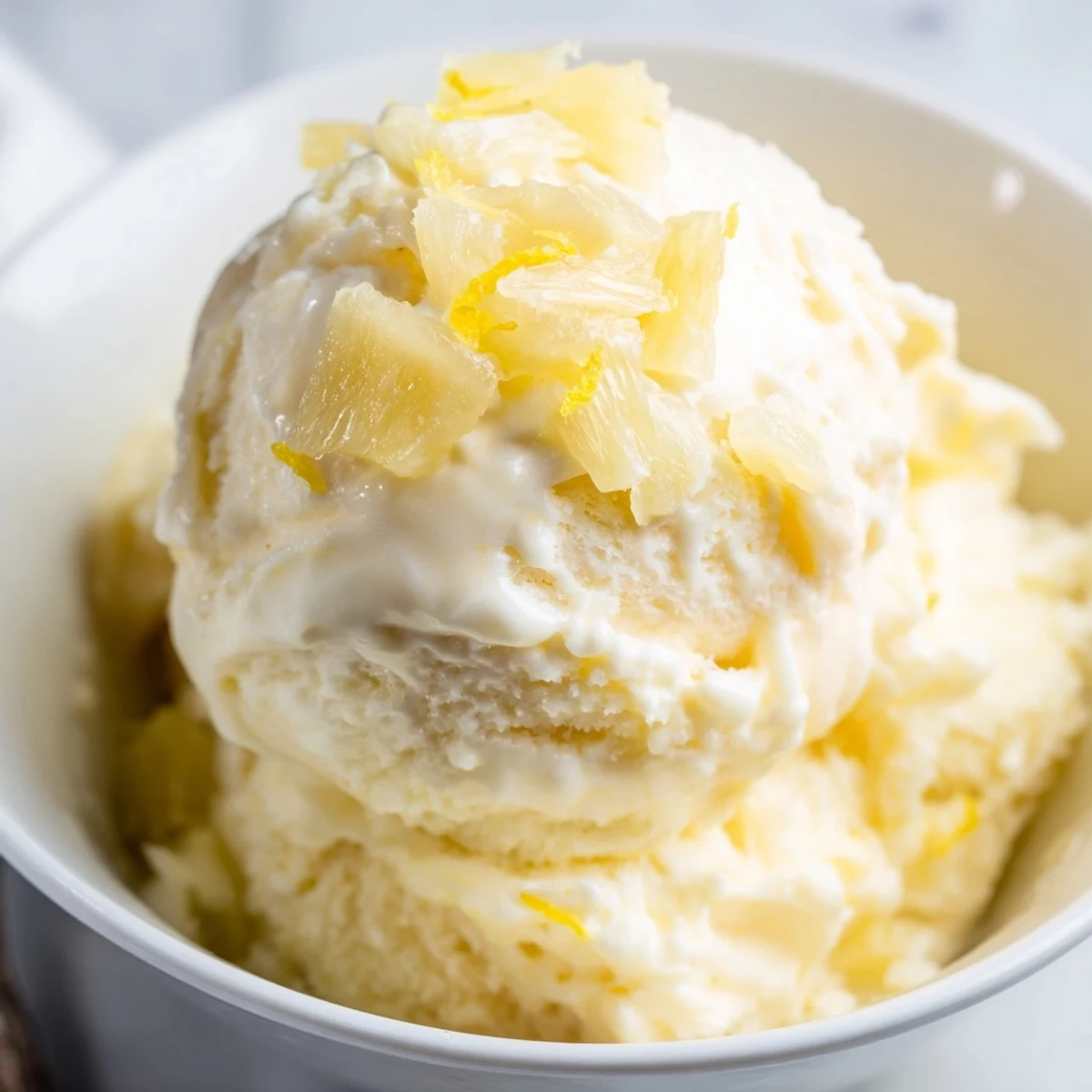 A bowl of Creamy Pineapple Ice Cream garnished with toasted coconut flakes