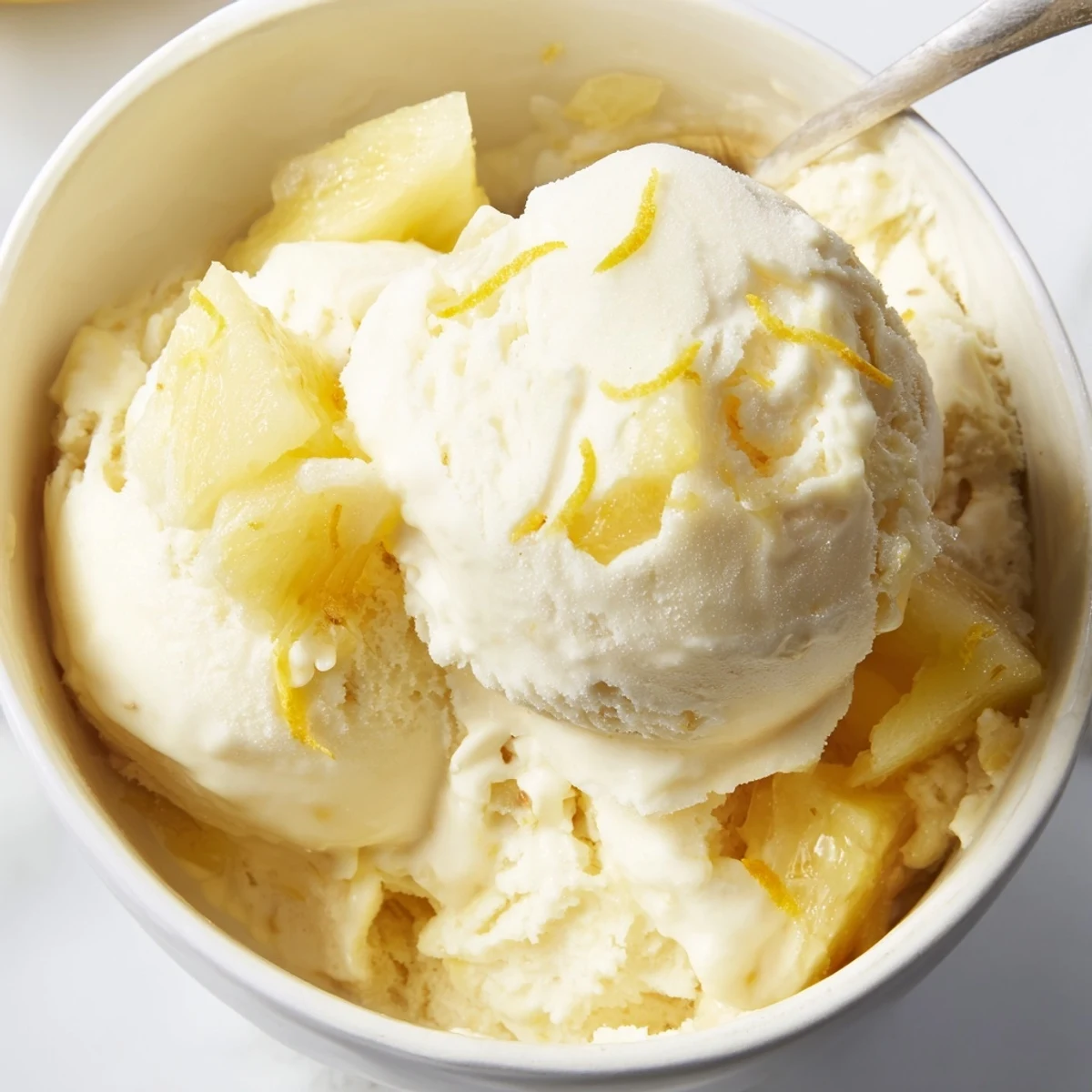 Homemade Creamy Pineapple Ice Cream, velvety texture melting beside a lemon wedge